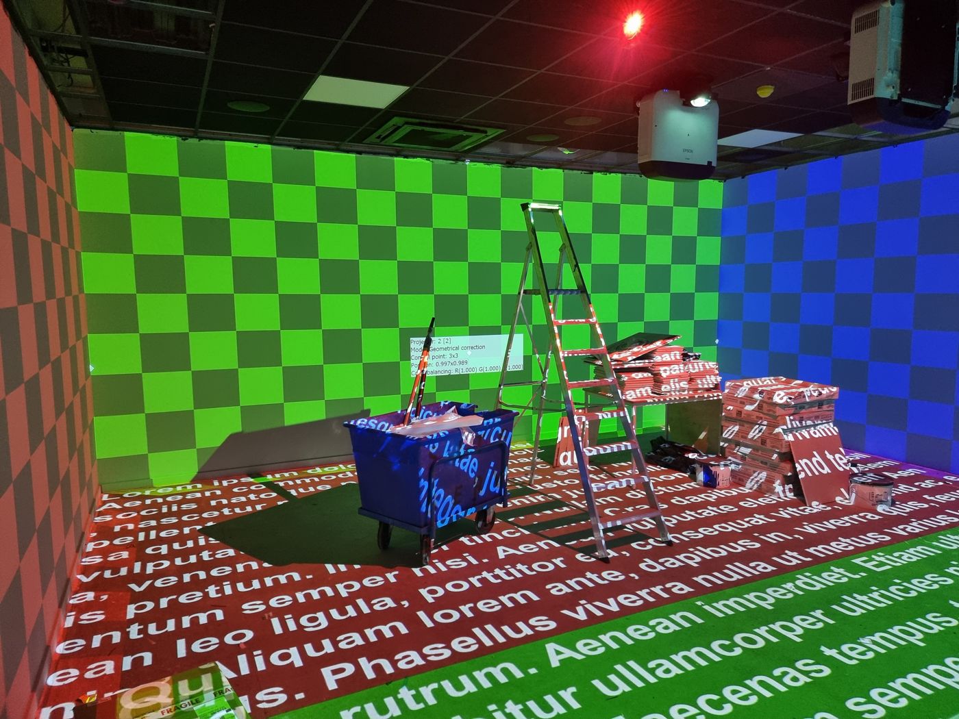 Checkerboard test patterns projected on three walls and text on the floor during projector calibration
