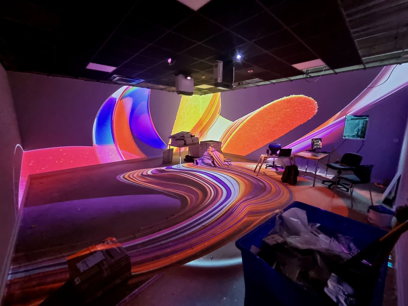 An immersive room mid-build with colourful content projected across the walls and floor