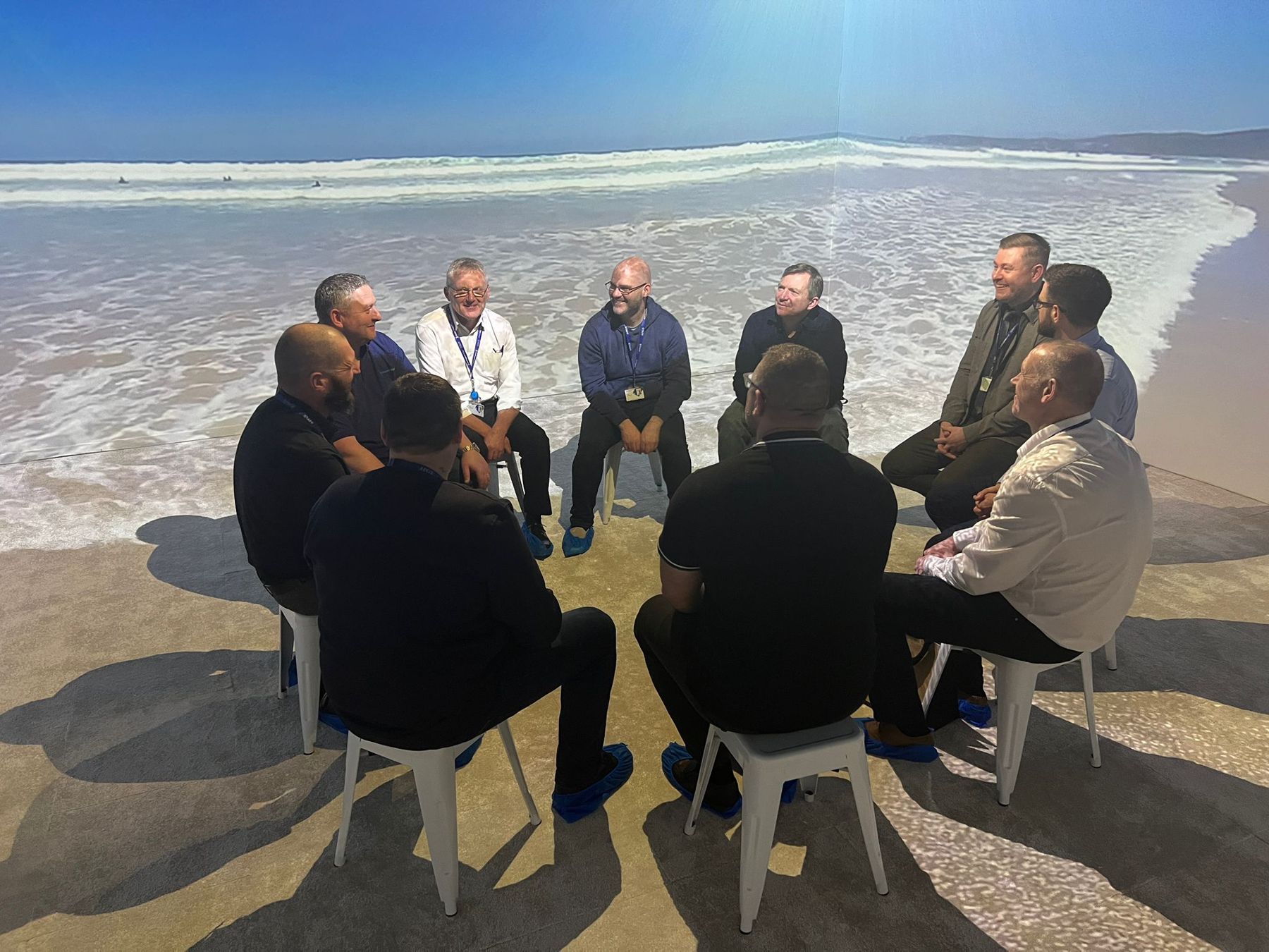 A group seated in the Darlington College immersive classroom with a beach scene projected on the walls and floor